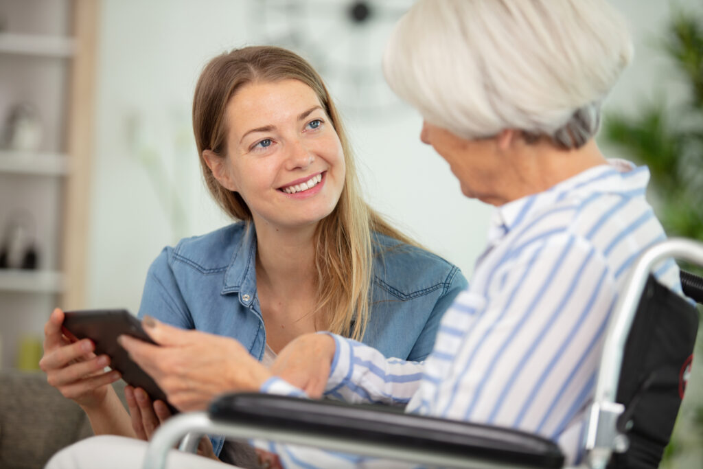 young lady with elderly woman using digital tablet
